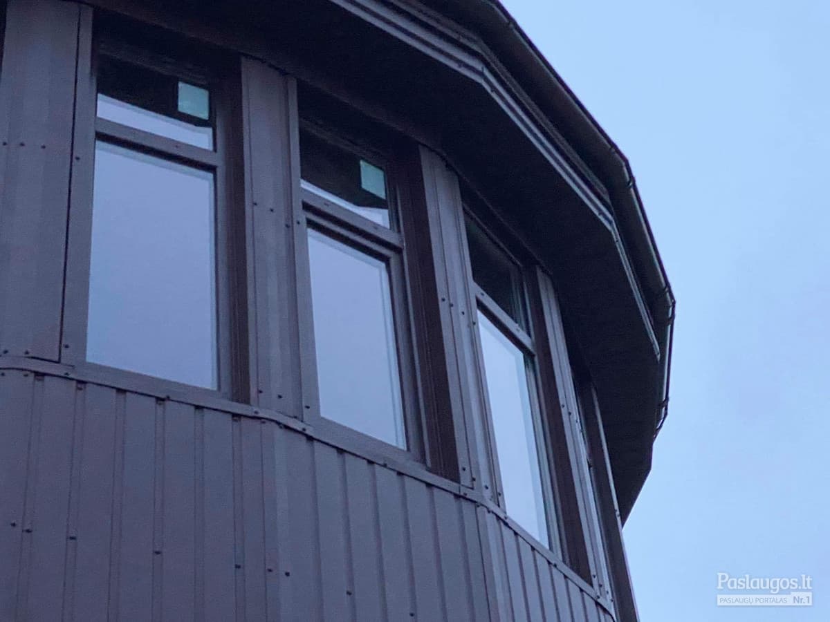 Apvalaus bokšto fasado skardinimas – tamsiai rudas metalas, stačiakampiai langai