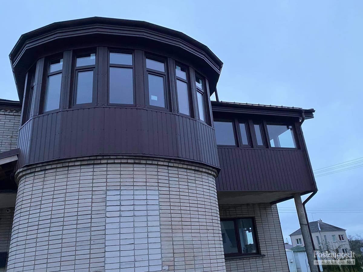Apvalus namo bokštelis su metaline apdaila – tamsiai rudas, ant plytos pamato