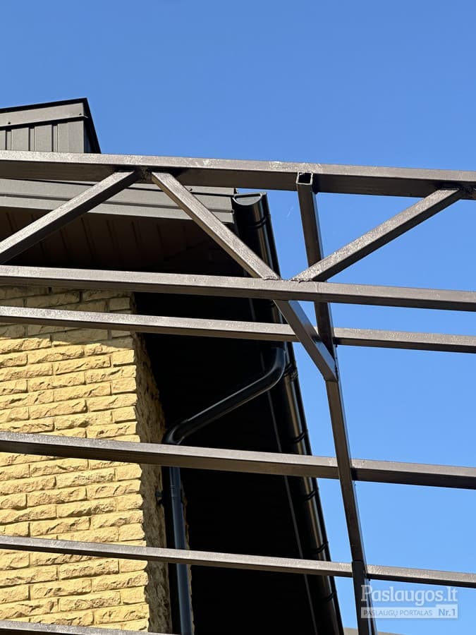 Plieno karkaso pergola iš apačios – geometrinis rėmas prieš mėlyną dangų