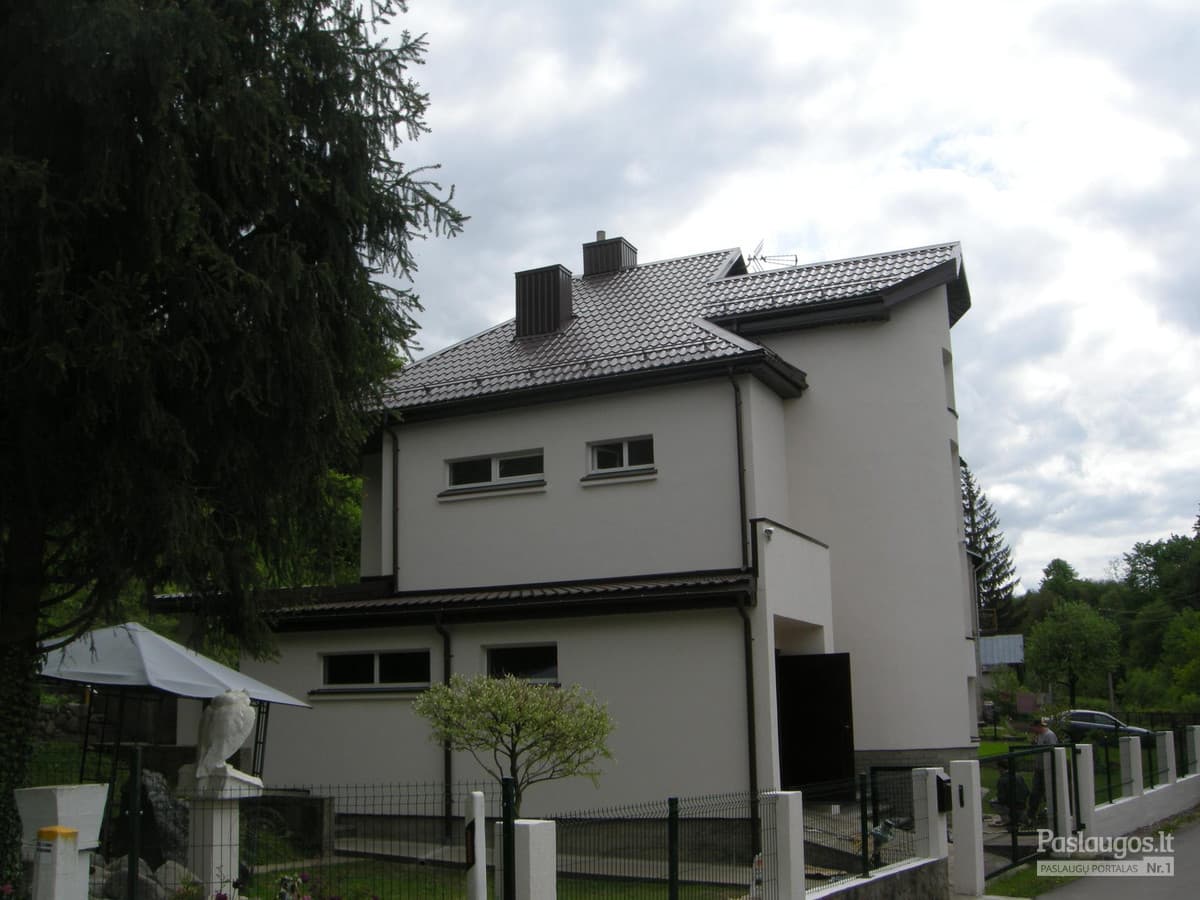 Baltas privatus namas su tamsiai pilku čerpių stogu – priekinės gatvės vaizdas