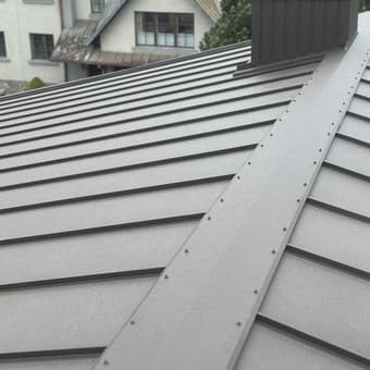 Pilkos skardos stogo kraigė iš arti – lygios siūlės ant privataus namo