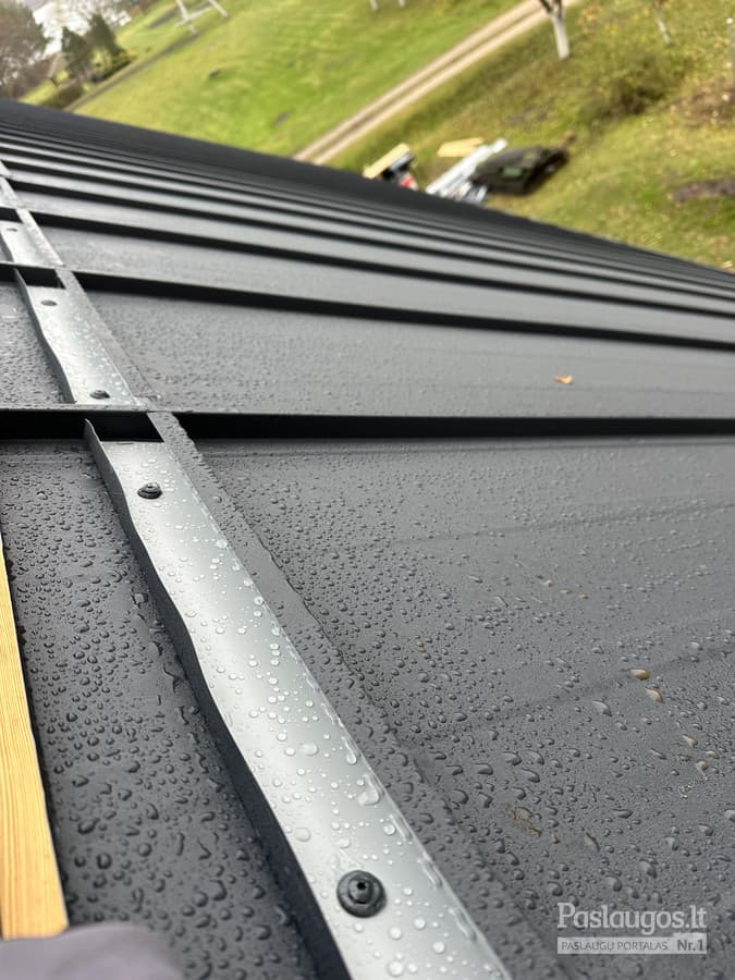 Tamsios skardos stogo briaunos detalė lietaus lašeliais – vandeniui atspari danga