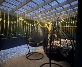 Medinė pergola vakare – dekoratyvios lemputės, kėdžių houpai