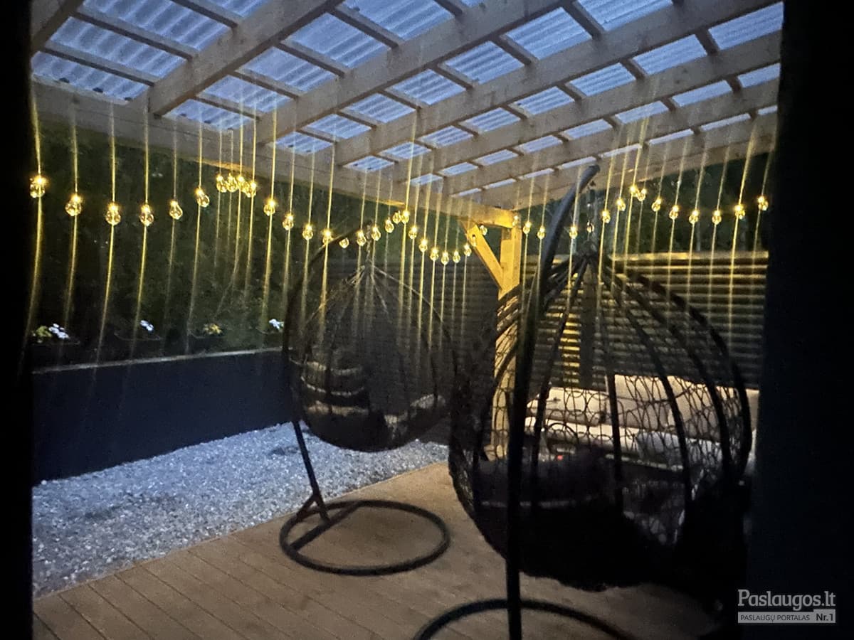 Medinė pergola naktį su girliandų apšvietimu – jaukus lauko kampelis
